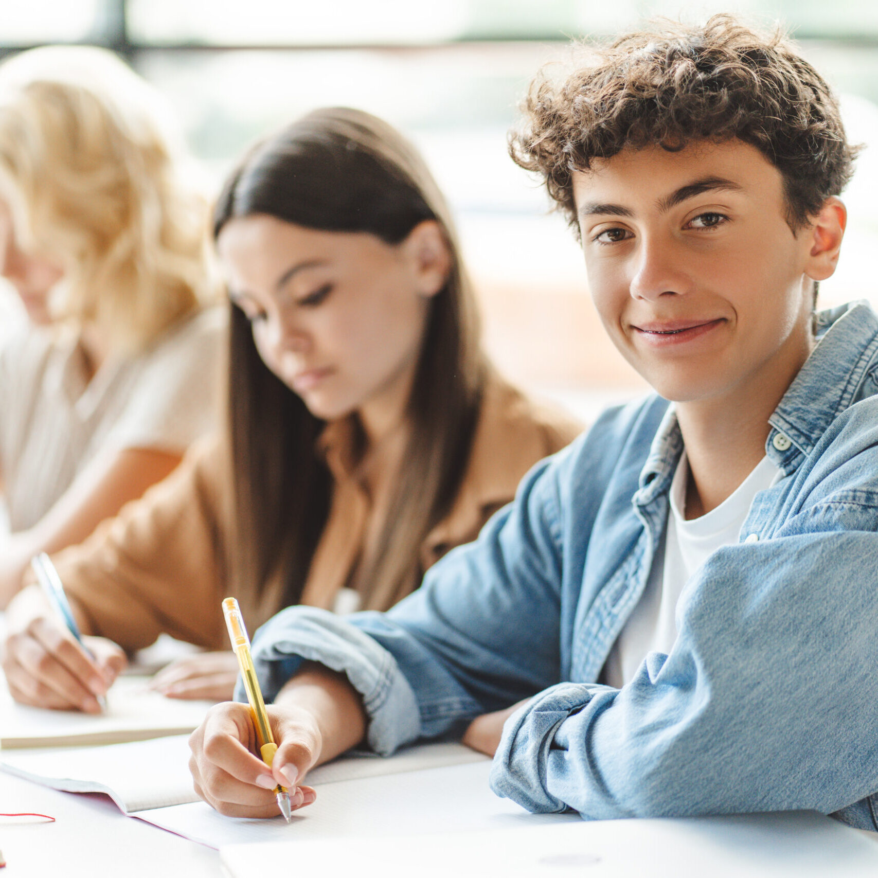 Portrait of smart schoolmates  studying together, learning language, exam preparation sitting in modern classroom. Back to school, lesson, education concept